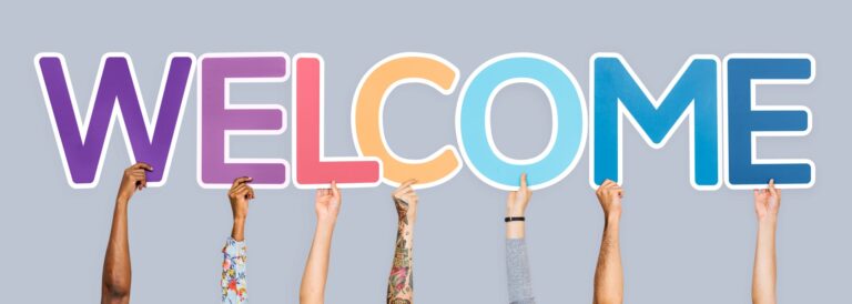 Texto "Welcome" ("Bem-vindo" em inglês) com letras grandes, cada uma com uma cor. Cada letra é segurada por uma mão diferente pela parte de baixo.
