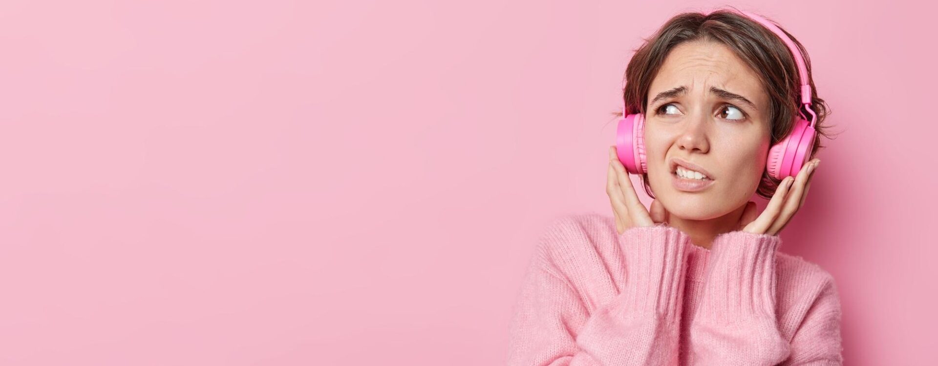 Mulher usando fones ouvido e fazendo careta.