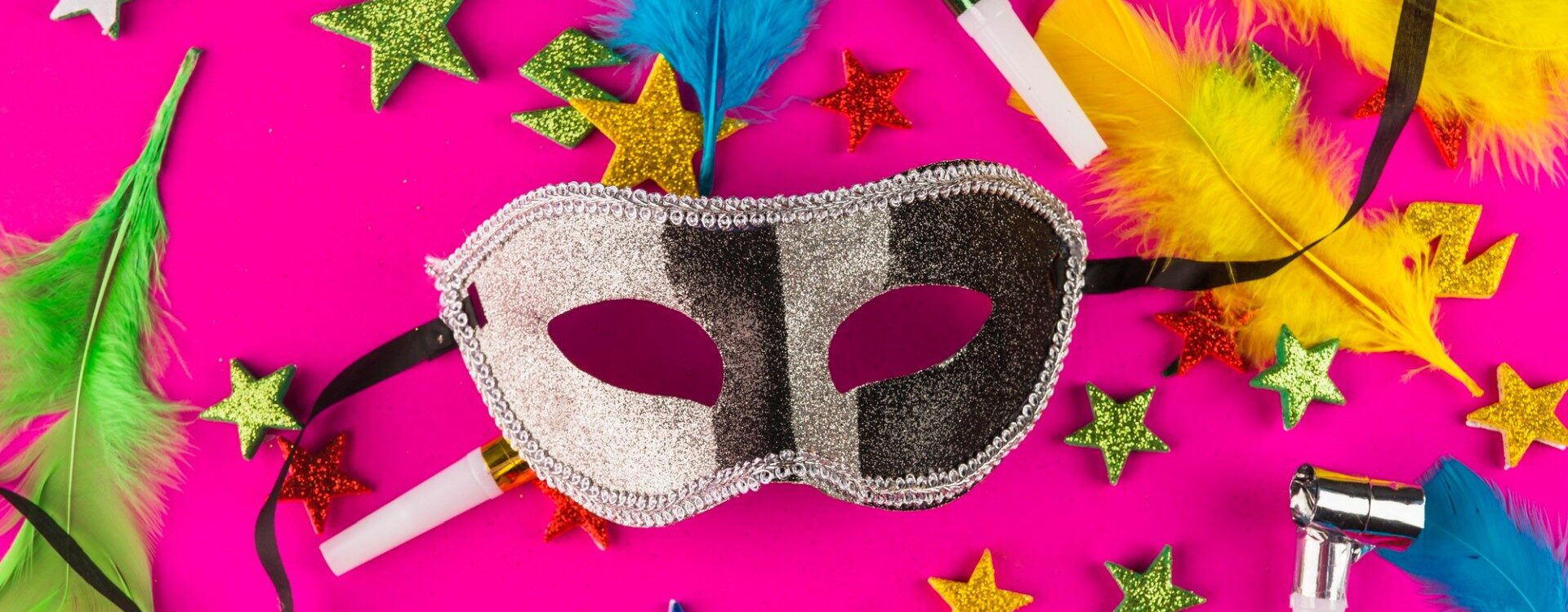 Máscara de carnaval com decorações de carnaval ao fundo.