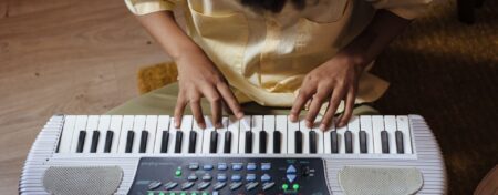 Criança tocando um teclado pequeno dentro de casa.